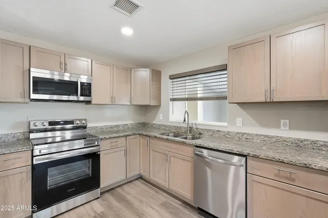 a kitchen with granite countertop a sink stainless steel appliances and cabinets