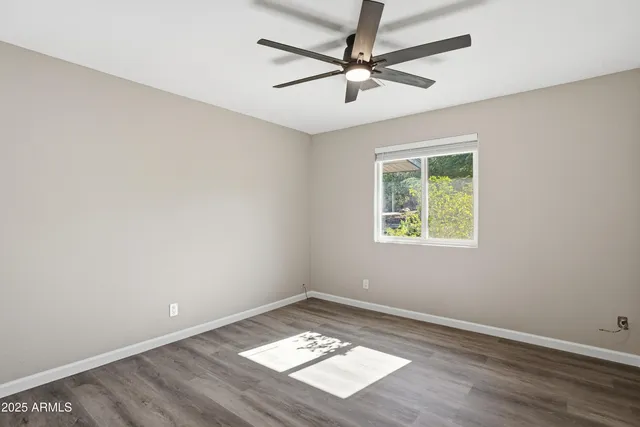 an empty room with wooden floor ceiling fan and windows