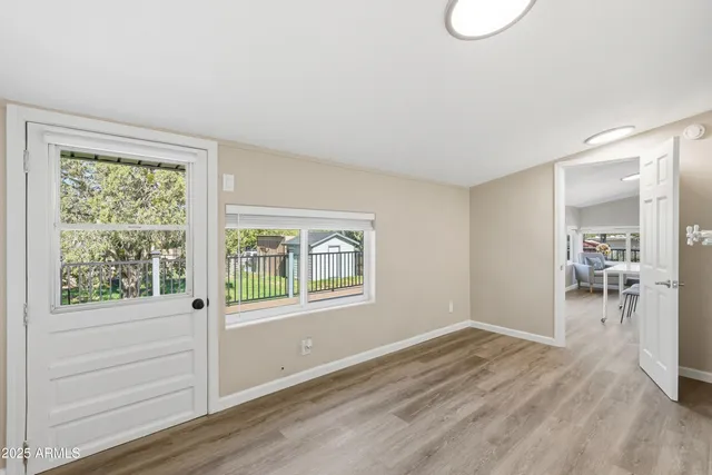 a view of empty room with wooden floor and fan
