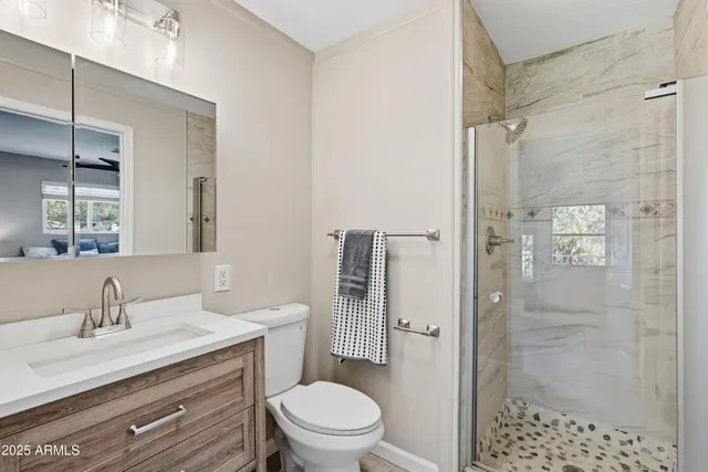 a bathroom with a granite countertop sink toilet a mirror a shower and a bathtub