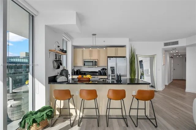 a kitchen with stainless steel appliances kitchen island granite countertop a table chairs and a refrigerator