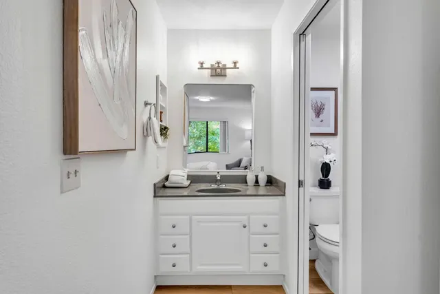 a bathroom with a granite countertop sink a toilet a mirror and shower