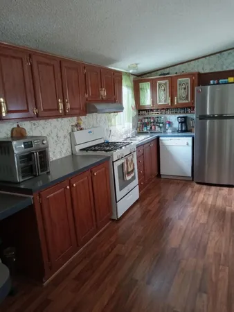 a kitchen with stainless steel appliances granite countertop wooden cabinets a stove a sink and dishwasher with wooden floor