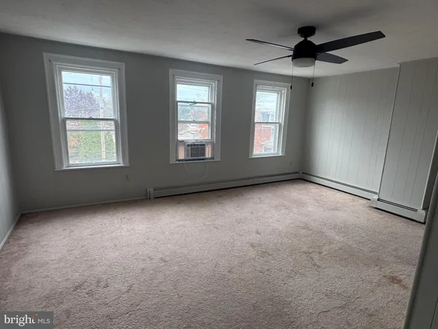 an empty room with windows and fan