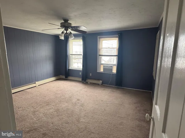 an empty room with windows and chandelier fan