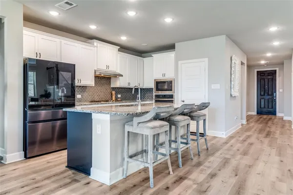 a kitchen with stainless steel appliances kitchen island granite countertop a refrigerator and a stove top oven