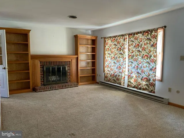 a view of an empty room with a fireplace and a window