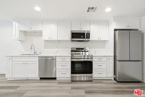a kitchen with cabinets stainless steel appliances and wooden floor