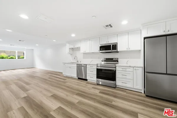 a kitchen with granite countertop a refrigerator and a stove top oven
