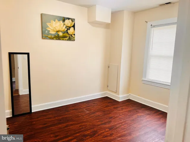 an empty room with wooden floor and window