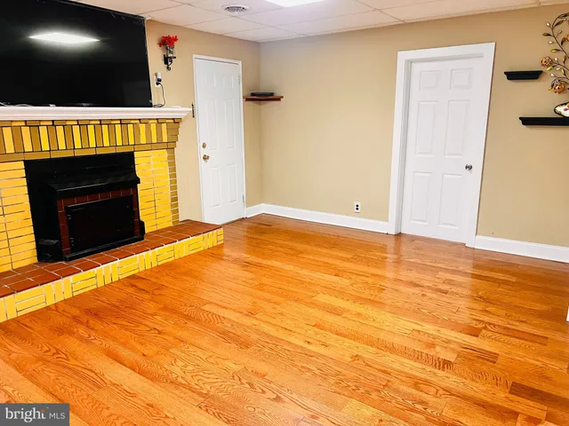 a view of an empty room with wooden floor and a fireplace