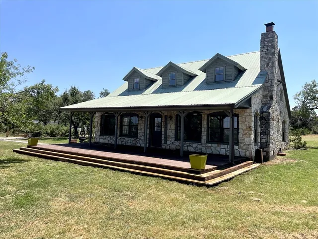a backyard of a house with table and chairs under an umbrella