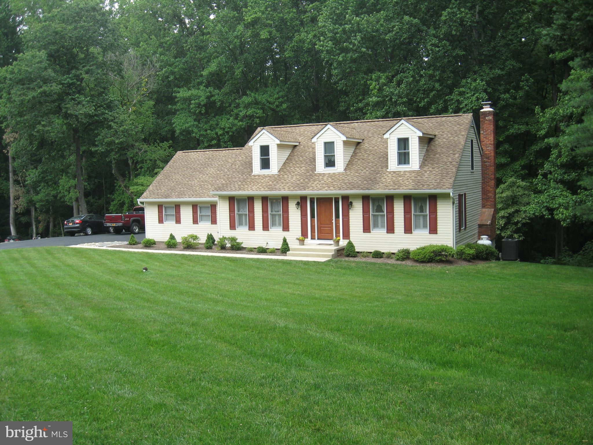 a view of house with a big yard and large trees