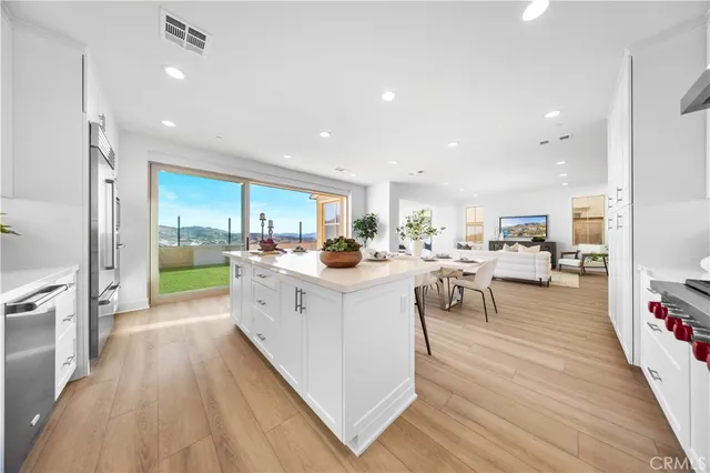 a kitchen with a sink and white cabinets with wooden floor