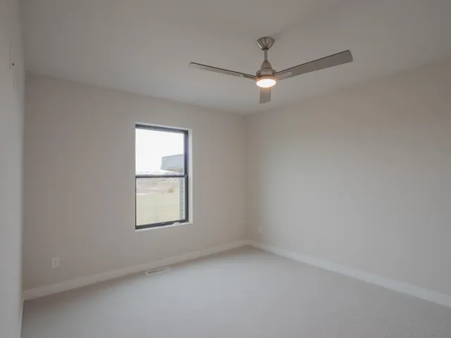 an empty room with a window and ceiling fan