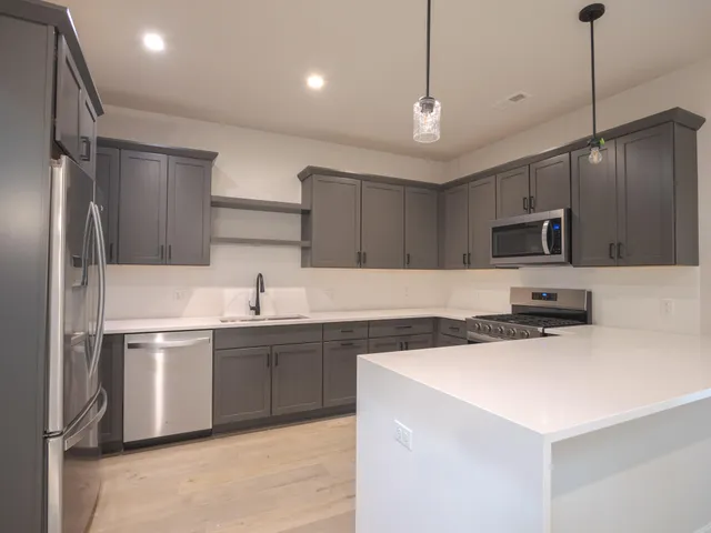a kitchen with stainless steel appliances a sink a stove a refrigerator and cabinets
