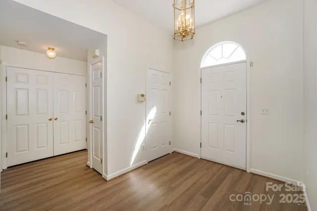 an empty room with wooden floor closet and windows