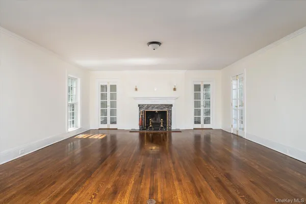 a view of an empty room with wooden floor fireplace and a window