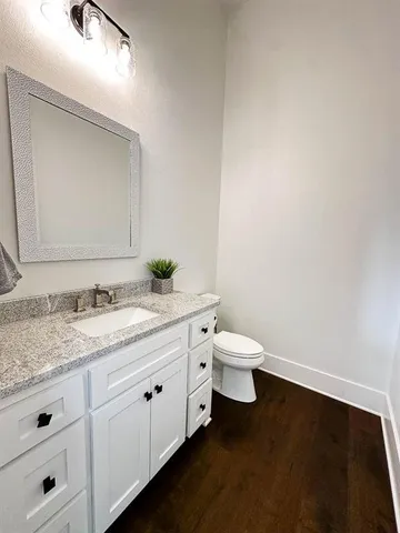 a bathroom with a granite countertop toilet and a sink