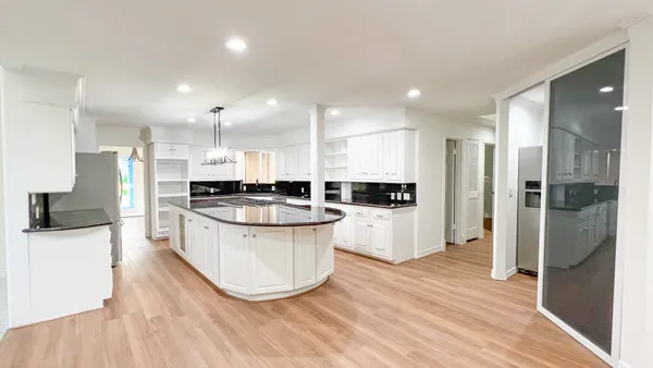 a large kitchen with stainless steel appliances a refrigerator a sink a stove a microwave and wooden floor