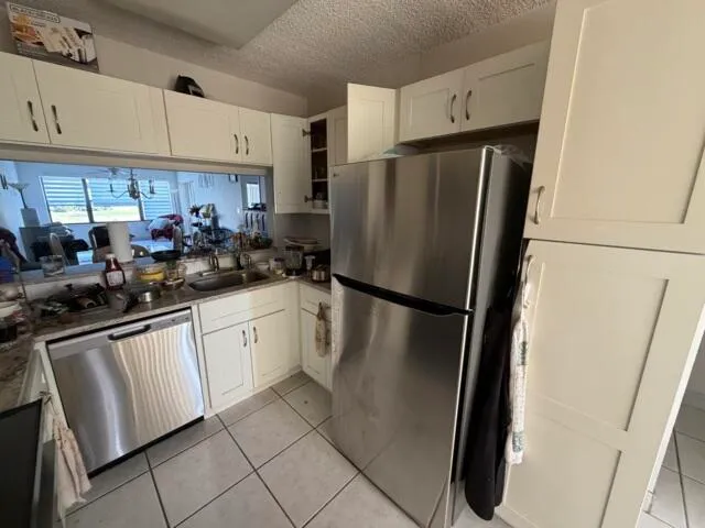 a kitchen with stainless steel appliances a refrigerator a sink a stove a washer dryer and white cabinets