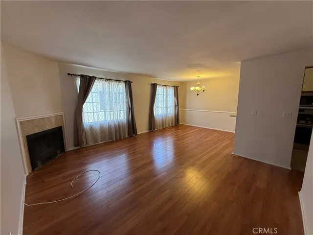 an empty room with wooden floor fireplace and staircase