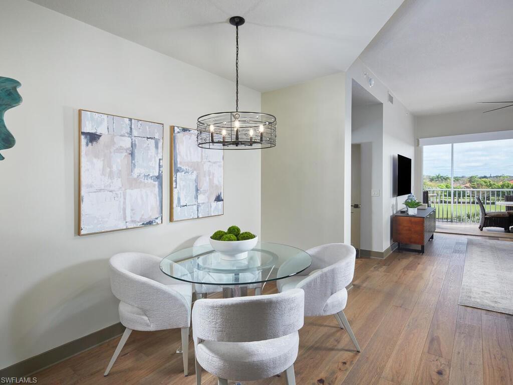 7655 Pebble Creek Circle, Unit 404 Naples, FL 34108 - Photo 5 of 19 a dining room with furniture a chandelier and wooden floor