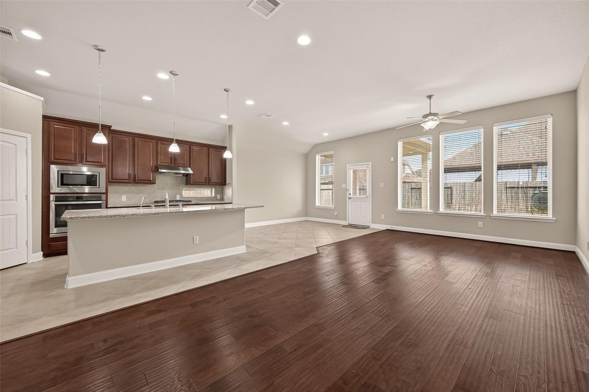 107 Angel Hollow Lane Rosenberg, TX 77469 - Photo 13 of 50 Warm wood floors and a wall of windows give this living room an energized, "stay-a-while" vibe, all with a lovely view of the backyard.