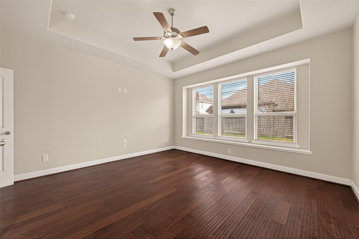 107 Angel Hollow Lane Rosenberg, TX 77469 - Photo 14 of 50 A sanctuary in every sense, the primary bedroom features an elegant tray ceiling and multiple windows to make every morning feel like a fresh start.