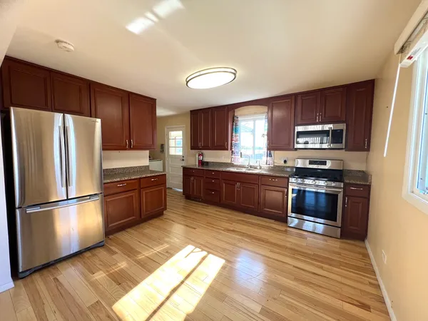 a kitchen with granite countertop wooden cabinets a refrigerator and a stove top oven