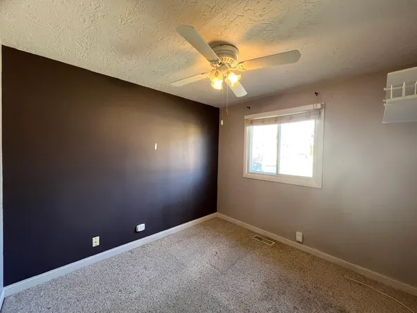 an empty room with a window and a fan