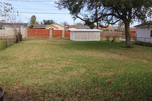 a view of a house with a yard and a large tree