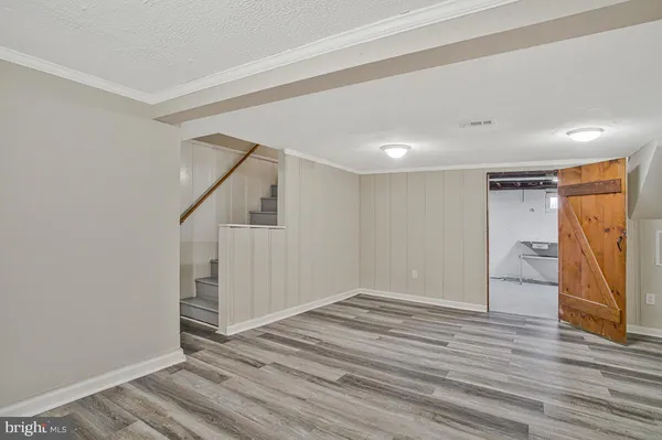 a view of an empty room with wooden floor and stairs