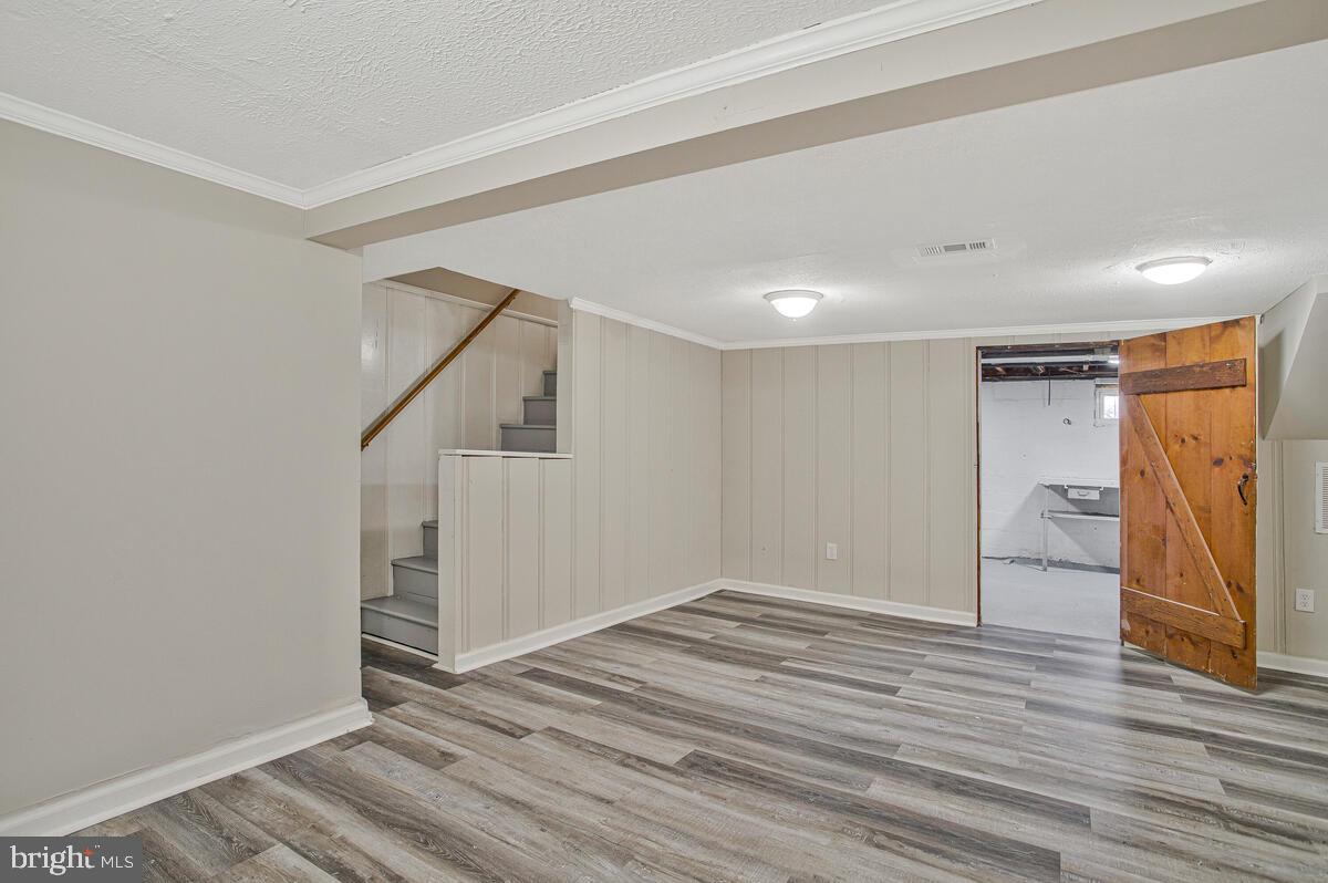 119 West Edgevale Road Baltimore, MD 21225 - Photo 28 of 37 a view of an empty room with wooden floor and stairs