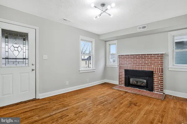 a view of empty room with wooden floor and fireplace