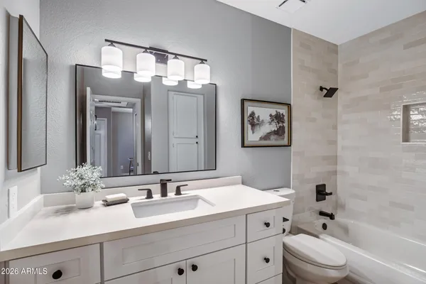 a bathroom with a bathtub shower sink vanity mirror and toilet