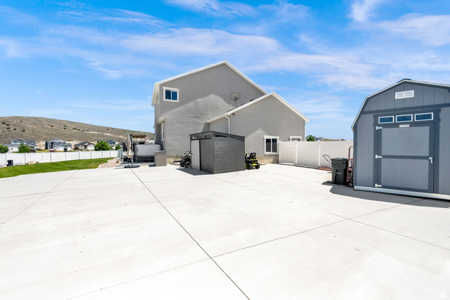 1857 Thunder Gulch Road Eagle Mountain, UT 84005 - Photo 41 of 50 Expansive concrete patio area featuring a detached storage shed, white vinyl fencing, and a separate small storage unit