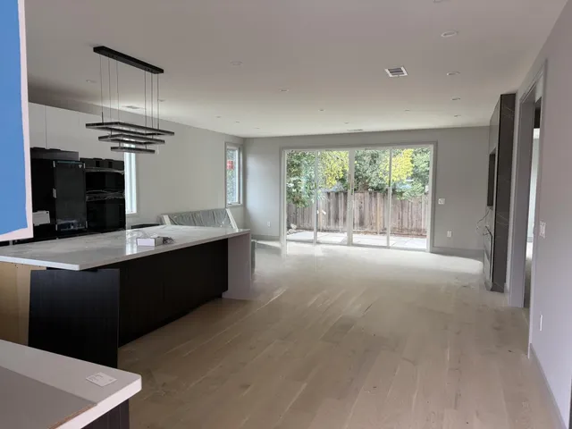 a living room with stainless steel appliances kitchen island granite countertop a cabinets and a wooden floor