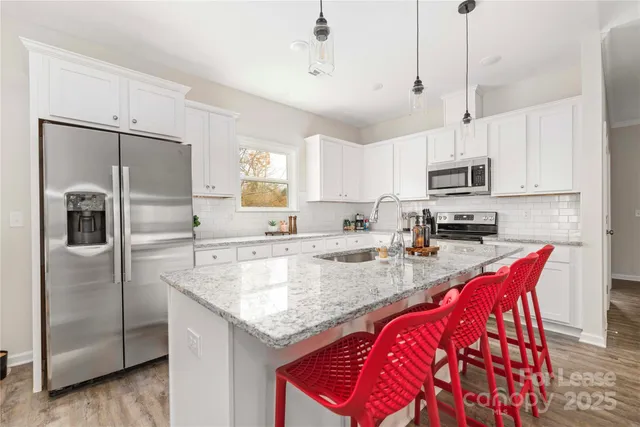 a kitchen with stainless steel appliances granite countertop a sink a stove a refrigerator a center island a stove and cabinets