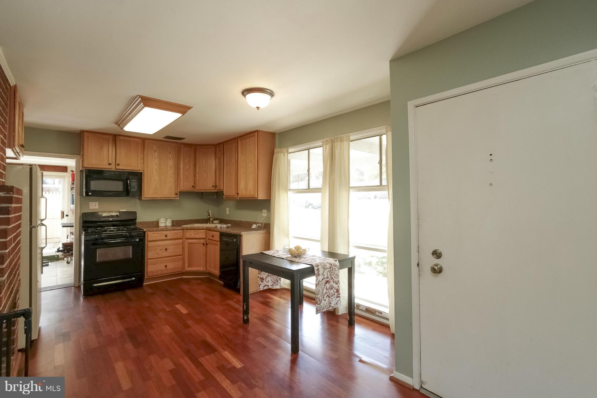 7207 Highland Street Springfield, VA 22150 - Photo 4 of 26 a kitchen with stainless steel appliances granite countertop a stove top oven a sink dishwasher a dining table and chairs with wooden floor