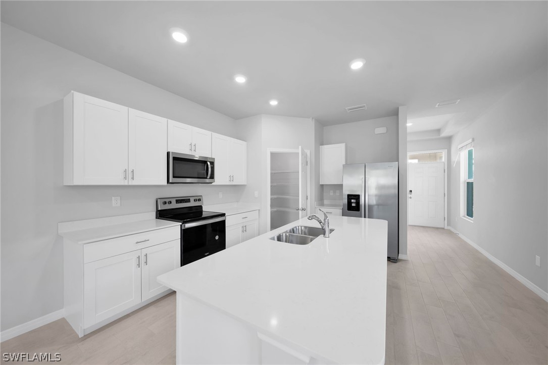 900 Friendship Circle LaBelle, FL 33935 - Photo 5 of 21 a large white kitchen with a refrigerator a stove top oven a sink and cabinets