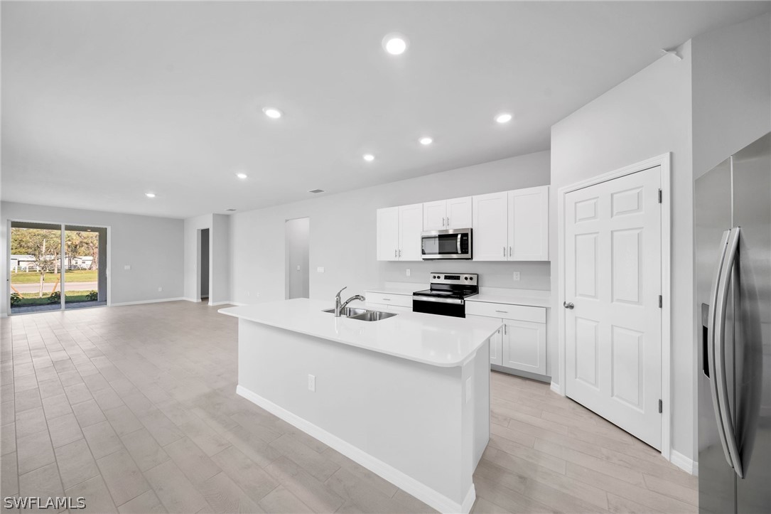 900 Friendship Circle LaBelle, FL 33935 - Photo 6 of 21 a kitchen with stainless steel appliances a sink a stove a refrigerator cabinets and a window