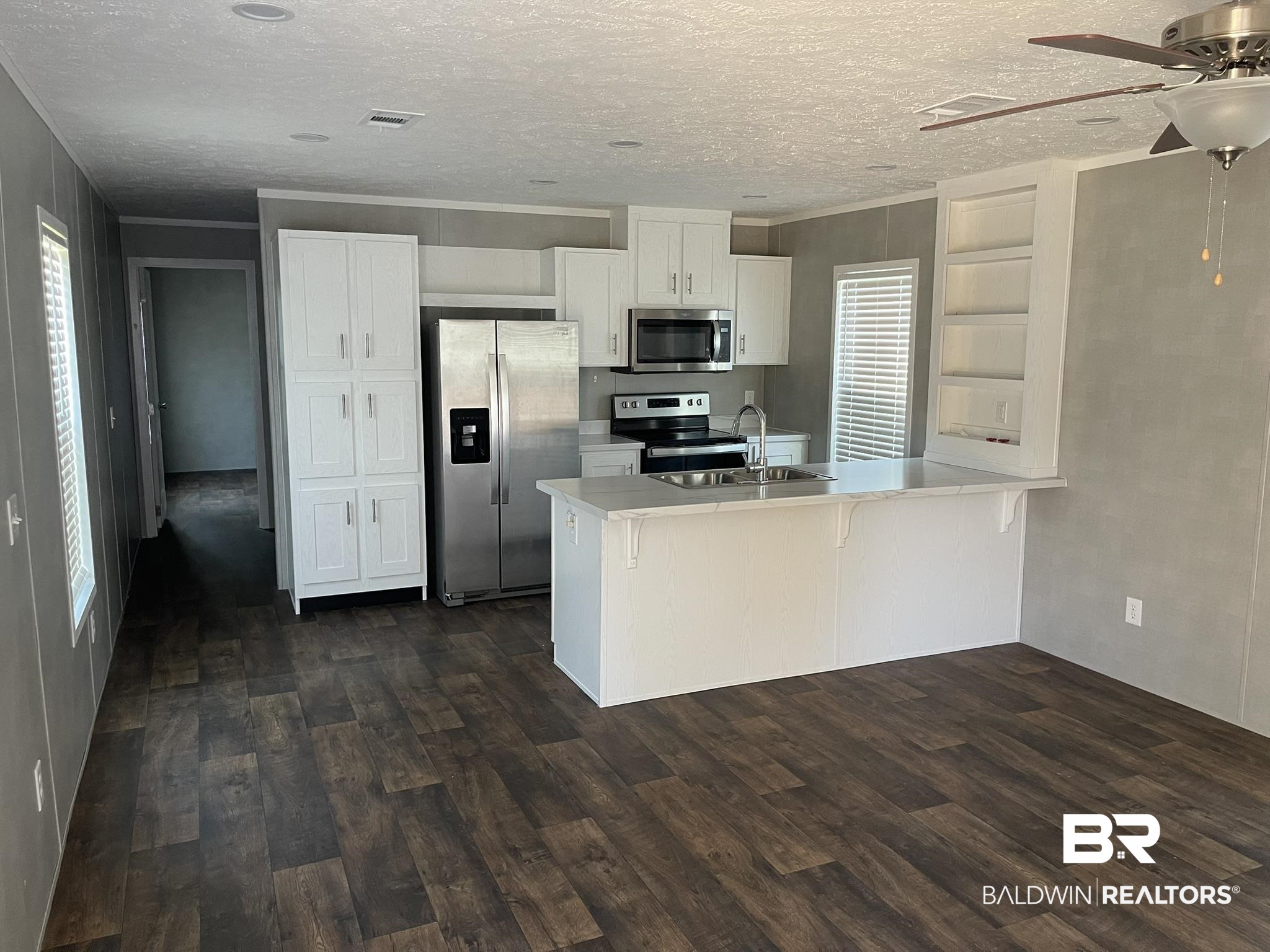 9202 Bay Pnes Road Elberta, AL 36530 - Photo 3 of 17 Kitchen with white cabinetry, light countertops, appliances with stainless steel finishes, a peninsula, and dark wood finished floors