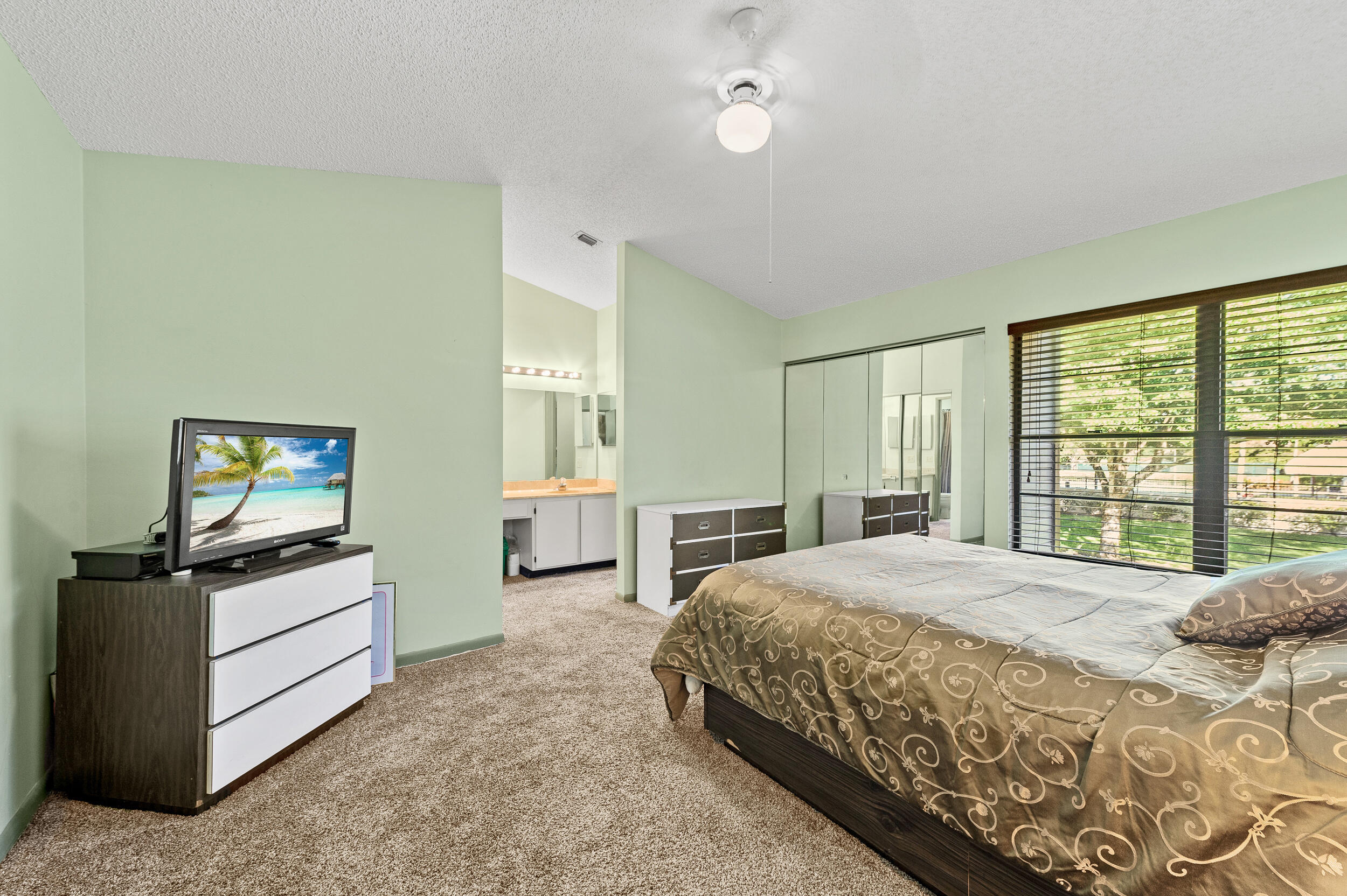 22384 Thousand Pines Lane Boca Raton, FL 33428 - Photo 32 of 45 a spacious bedroom with a bed and a flat tv screen on dresser