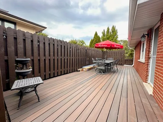 a balcony with wooden floor table and chairs