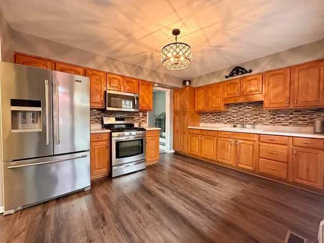 a kitchen with stainless steel appliances granite countertop a refrigerator a stove top oven a sink and dishwasher