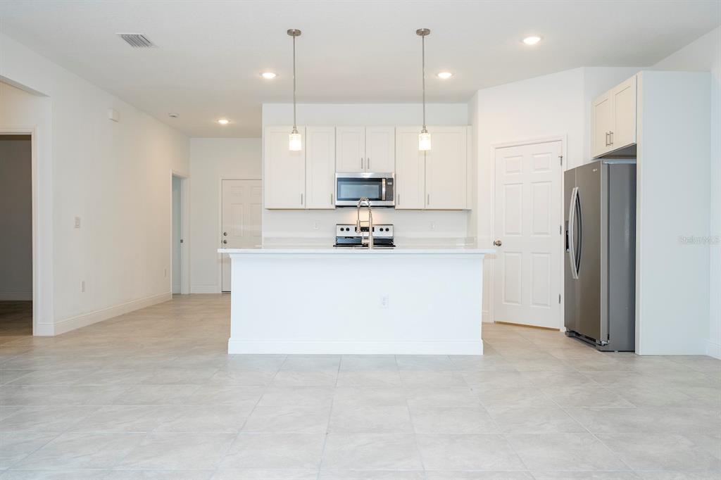 208 Locust Pass Ocala, FL 34472 - Photo 22 of 71 a kitchen with kitchen island a refrigerator a sink and white cabinets