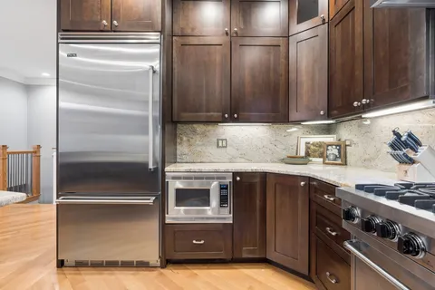 a kitchen with granite countertop a refrigerator and a stove top oven