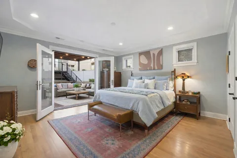 a spacious bedroom with a bed a mirror and a large window