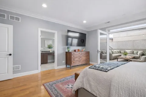 a spacious bedroom with a bed a dresser and wooden floor